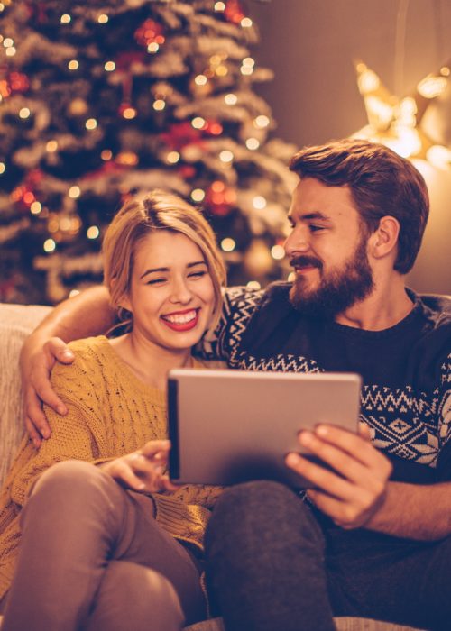 Couple sur canapé - Tablette connectée - Noël